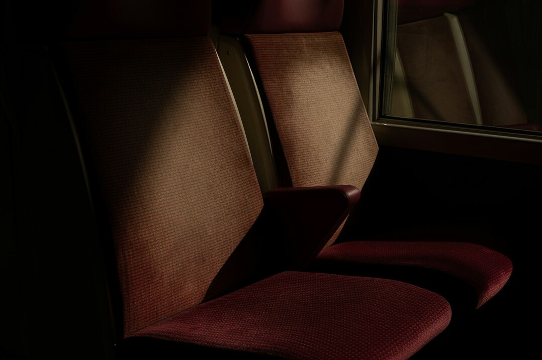 Rows of empty red velvet theatre seats under dim ambient light